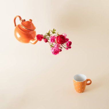 Turuncu çaydanlık, çeşitli yaz çiçekleri ve parlak arka planda çay fincanı. Asgari yaratıcı kavram.