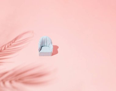 Kum rengi arka planda tropikal yaprak gölgesinde mavi koltuk. Düz yatıyordu. Palmiye yaprağı ile en az yaz konsepti. Yaratıcı eşuzay.