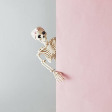 Bir kadının iskeleti duvarın arkasından dışarı bakıyor. Yaratıcı Cadılar Bayramı asgari konsepti. Asgari korku duvar kâğıdı. 31 Ekim parti davetiye kartı kopyalama alanı ile.