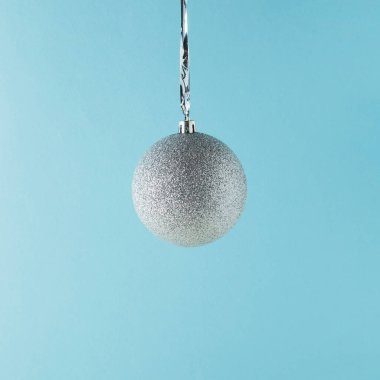 Pastel mavi arka planda parlak bir Noel süsü. Yeni yıl partisi geçmişi. Asgari biçim.