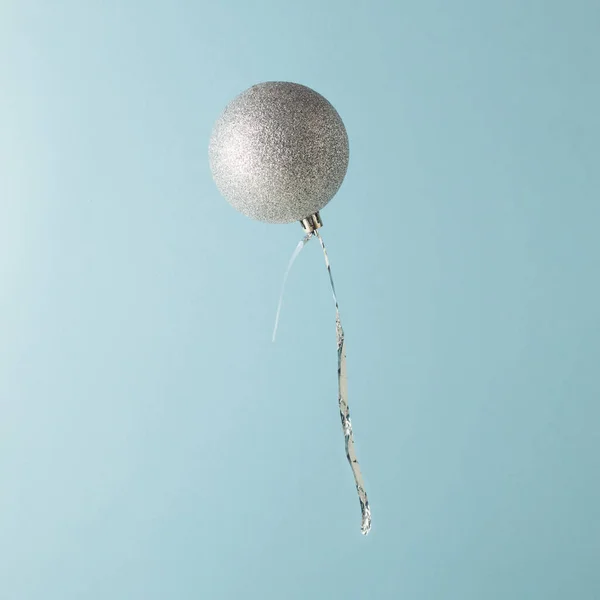 Balloon made of glitter Christmas bauble decoration on blue background. Minimal Christmas concept.
