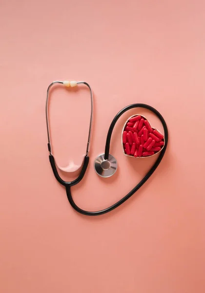 Stethoscope with red heart pills. Minimalist concept of health and love. Flat lay