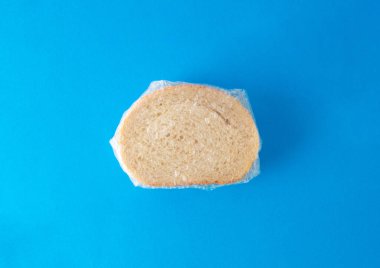 Mavi arka planda folyoya sarılı susam tohumlu taze beyaz ekmeğin genel görünümü. Fırın kavramı