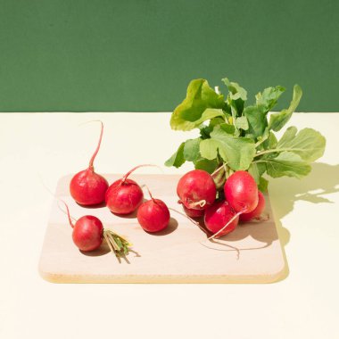 Mutfak tahtasındaki taze turp kökleri yeşil kontrast arka planda. Yaratıcı minimalist kavram