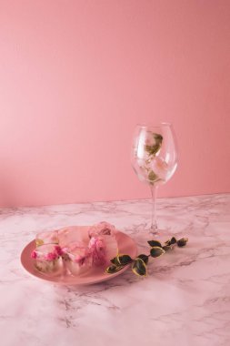Buz küplerindeki küçük güzel pembe çiçekler ve pembe tabakta mermer ve pembe arka planda taç yaprakları olan cam..