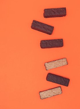 Çikolatalı gofretler turuncu arka planda dizilmiş. Boşluğu kopyala