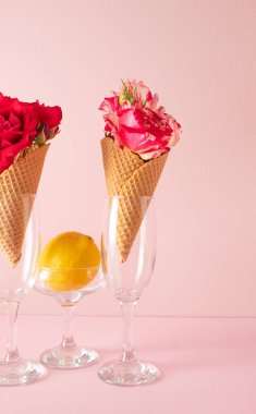 Renkli çiçekli dondurma külahı ve pastel pembe arka planda limon. Asgari yaz konsepti.