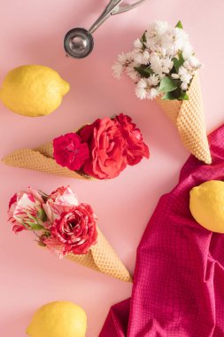 Renkli çiçekli dondurma külahı ve pastel pembe arka planda limon. Düz yatıyordu. Asgari yaz konsepti.