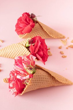 Pastel pembe arka planda renkli çiçekli dondurma külahı. Düz yatıyordu. Asgari yaz konsepti.