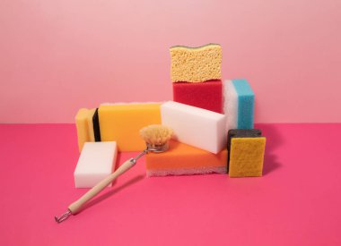 Temizlik süngerleri ve pastel pembe arka planda fırçayla yapılan yaratıcı bir düzenleme. Yaratıcı desinasyon fikri.