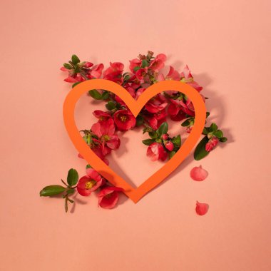 Pembe çiçeklerin yaratıcı kompozisyonu ve turuncu kağıt kalpli pembe arka plan. Çiçek düzlüğü yatıyordu. Boşluğu kopyala
