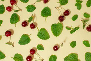 Bej arka planda nane yaprakları ve kiraz meyveleri için yaratıcı bir düzenleme. Düz yatıyordu