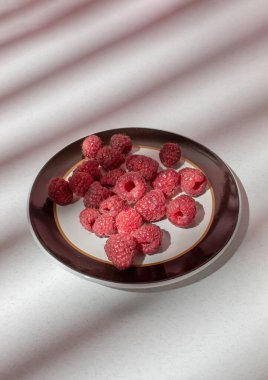 Masadaki gölgeli ışıklı tabakta taze ahududu. Yemek fotoğrafçılığı
