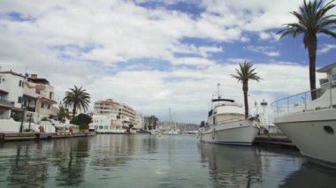 Bir tekneden gelen vurgulu kanal görüntüsü. Lüks evler. Yatlar. Avuçlar. Kanalda yüzen ördekler. Bulutlu mavi gökyüzü. Zevk gemisine binmek. 