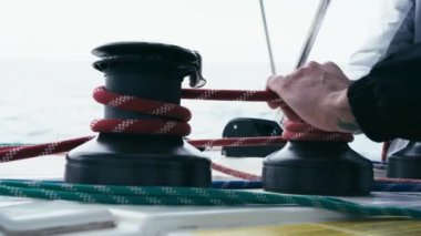 Katamaranın vinçlerindeki sarmalı halatlara yakın çekim. İnsanlar vinçlerde kırmızı ipleri kuruyor. Donanım. Katamaran gezisi. Yelkenli. 
