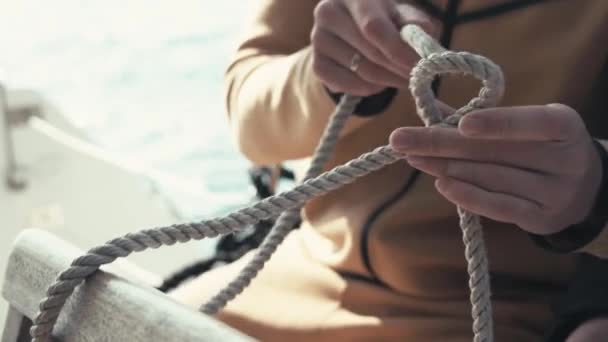 カタマランの船員は 海の結び目を結ぶ方法を示しています 手と結び目のクローズアップ カタマラン旅行 シーマン カタマランでの航海 — ストック動画