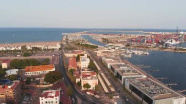 Valencia limanı ve plajı üzerinde uçuş. Yat ve rıhtımların tepeden tırnağa manzarası. Ufukta gün batımı var. 4K.