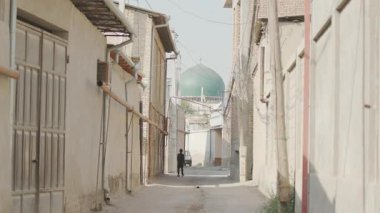 Doğu giysili bir kız yıkılmış caddelerde yürüyor. İleride bir cami görünüyor. 4K