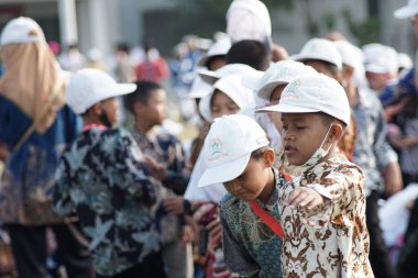 Lampung - 17 Ağustos 2023: Endonezyalı ilkokul öğrencileri Endonezya 'nın bağımsızlık gününde bayrak kaldırma töreninde batik ve beyaz şapka kullandılar
