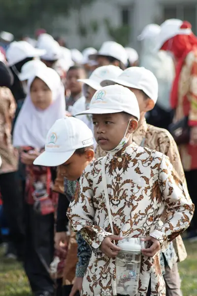 Lampung - 17 Ağustos 2023: Endonezyalı ilkokul öğrencileri Endonezya 'nın bağımsızlık gününde bayrak kaldırma töreninde batik ve beyaz şapka kullandılar