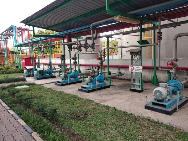 electric motors and pumps installation in a factory with caution of not using cellphone in Indonesian language