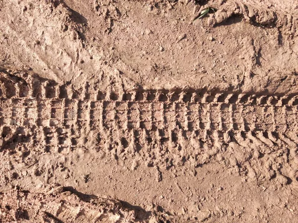 Toprak yolda motosiklet lastiği izleri.