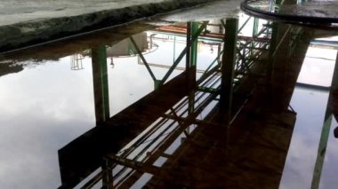 Yağmur suyu birikintilerinin yüzeyindeki fabrika borularının siluetinin yansıması.