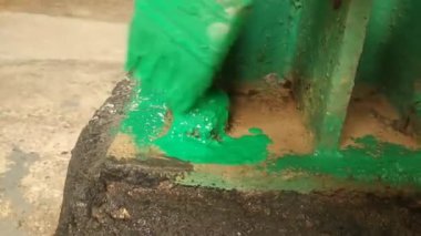 Fırça kullanarak yeşil boya uygulayan bir işçi.