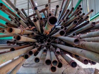 Eski bir fabrika deposunda depolanmış bir yığın kullanılmış iskele direği.