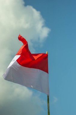 Öğleden sonra mavi gökyüzü ve beyaz bulutlarla dalgalanan Endonezya ulusal bayrağı