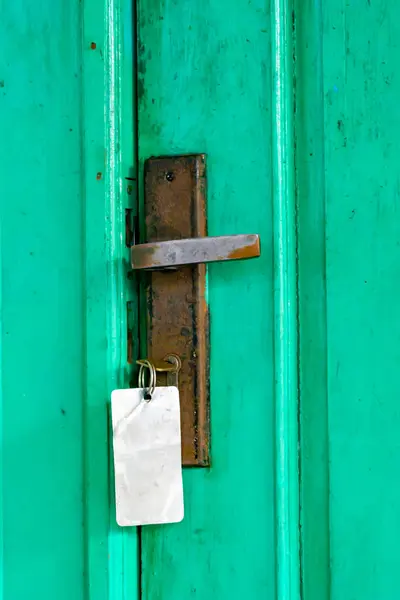 Eski paslı kapı kolu yeşil ahşap bir kapıda.