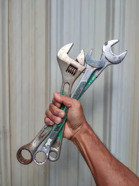 İngiliz anahtarı tutan Asyalı işçinin kırpılmış görüntüsü