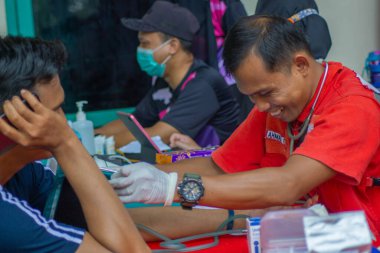Lampung Tengah, Lampung, Endonezya - 7 Aralık 2024: Bir sağlık çalışanı kan bağışı yapan birinin kan basıncını kontrol ediyor, Lampung, Endonezya 'daki bir etkinlikte.
