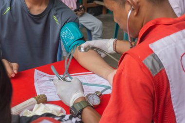 Lampung Tengah, Lampung, Endonezya - 7 Aralık 2024: Bir sağlık çalışanı kan bağışı yapan birinin kan basıncını kontrol ediyor, Lampung, Endonezya 'daki bir etkinlikte.