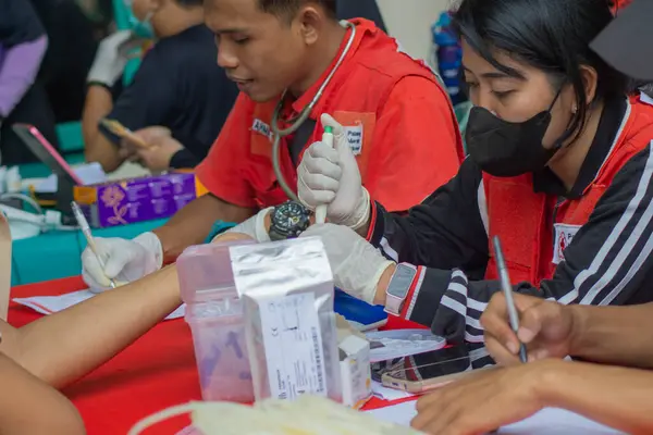 Lampung Tengah, Lampung, Endonezya - 7 Aralık 2024: Bir sağlık çalışanı Lampung, Endonezya 'da bir kan bağışı sırasında kan örneği alıyor