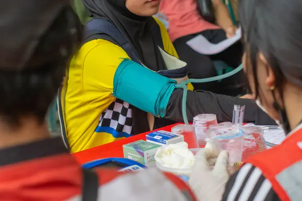 Bir sağlık çalışanı kan bağışı sırasında kan donörünün kan basıncını kontrol ediyor.