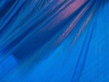 Pırıl pırıl yüzeyi olan mavi muşamba kumaş, kıvrımları ve katları var.