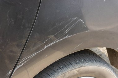 Direksiyonun arkasındaki panelde görünür çizikler olan siyah bir araba.