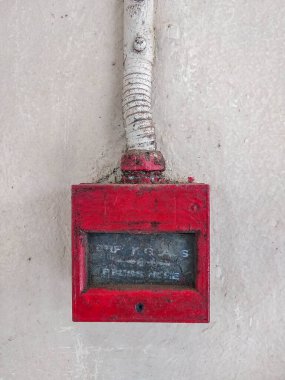 Beyaz duvardaki eski kırmızı yangın alarmı düğmesi