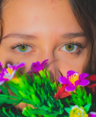 Yüzünü yapraklarla kaplayan genç ve güzel bir kadının yüzünü yakından çek. Doğal makyajlı kadın portresi