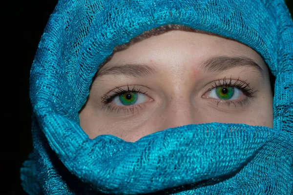green-eyed girl with her face wrapped in a green turban. close up of a girl with beautiful green eyes wearing a green hijab