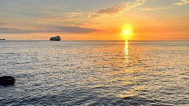 Güzel bir gün batımı ve ufukta bir gemi. Denizde altın saat