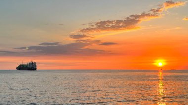 Güzel bir gün batımı ve ufukta bir gemi. Denizde altın saat