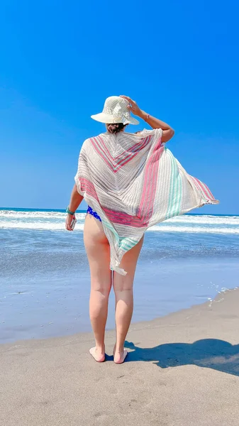 ビキニの女性のバックビューとショールでビーチを歩くわら帽子 夏休み — ストック写真