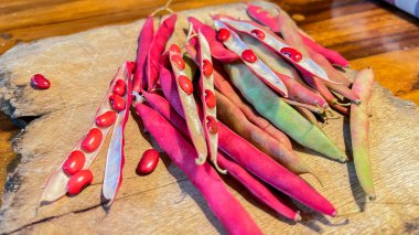 Tahta bir arka planda sepetteki kırmızı fasulyeler. Kapsüldeki kırmızı fasulyelerin yakın plan çekimi.