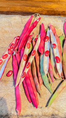 Tahta bir arka planda sepetteki kırmızı fasulyeler. Kapsüldeki kırmızı fasulyelerin yakın plan çekimi.