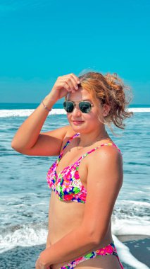 Güneşli bir günde, plajda pembe bikinili ve güneş gözlüklü güzel bir kadın. portre.