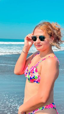 Güneşli bir günde, plajda pembe bikinili ve güneş gözlüklü güzel bir kadın. portre.