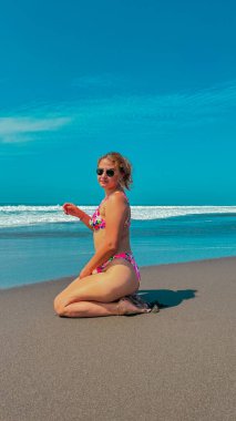 Bikinili güzel bir kadın denizde bir dalgada oturuyor..