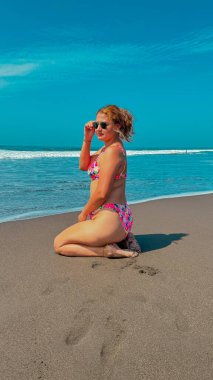 Bikinili güzel bir kadın denizde bir dalgada oturuyor..